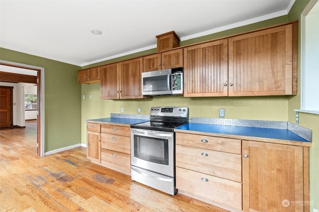 kitchen with ornamental molding, appliances with stainless steel finishes, and light hardwood / wood-style floors