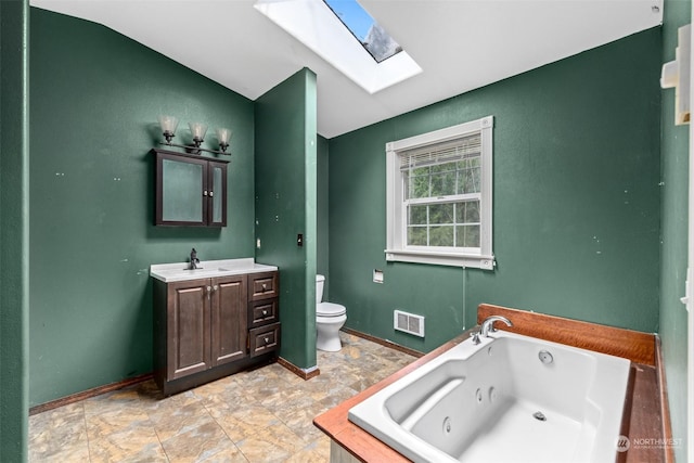 bathroom featuring vanity, toilet, a skylight, and a tub