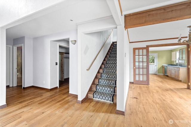 stairs featuring hardwood / wood-style flooring, a chandelier, and sink