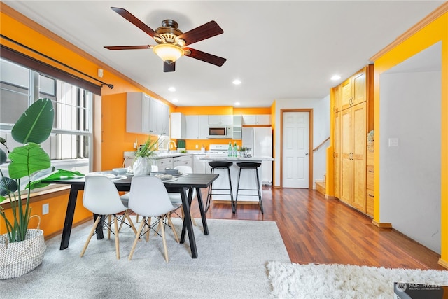 dining area with ceiling fan, wood-type flooring, sink, and ornamental molding