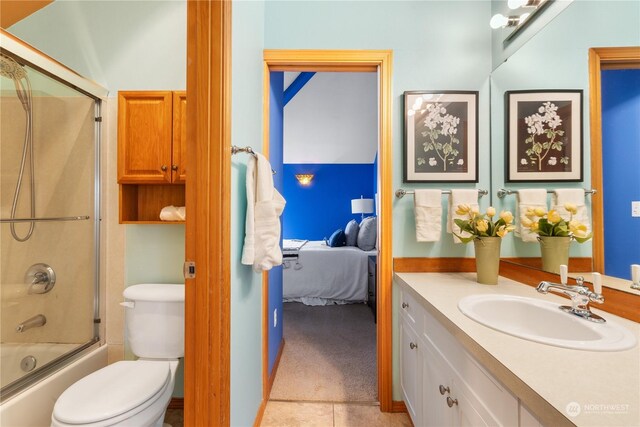 full bathroom with vanity, bath / shower combo with glass door, tile patterned floors, and toilet