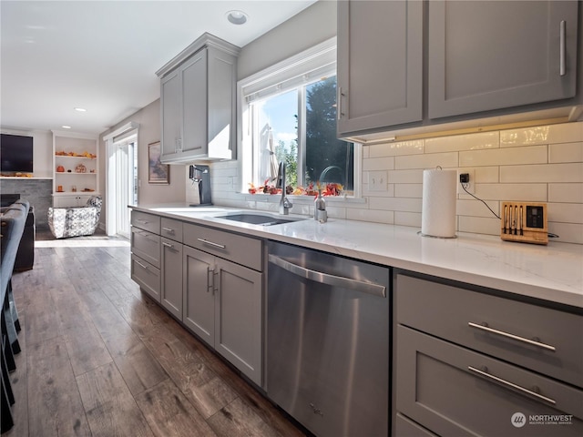 kitchen with dark wood-type flooring, sink, gray cabinetry, stainless steel dishwasher, and backsplash