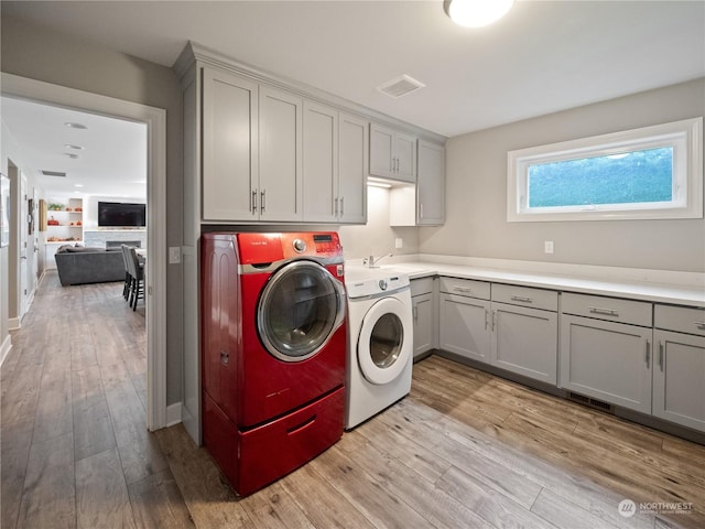 washroom featuring cabinets, light wood-type flooring, sink, and washer and clothes dryer