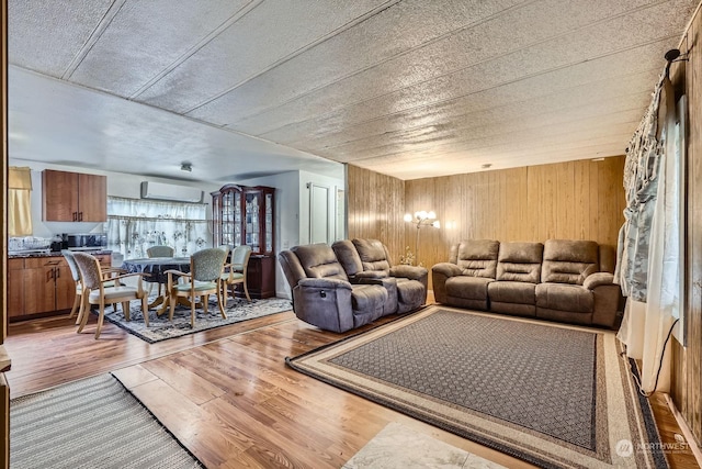 living room featuring hardwood / wood-style flooring, wooden walls, and a wall unit AC