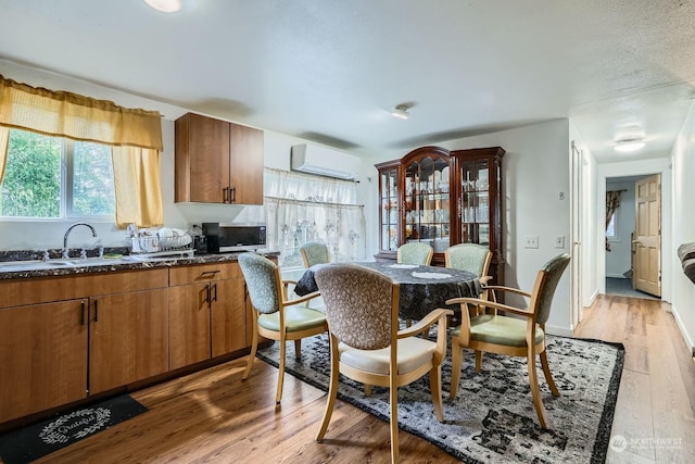 kitchen with dark stone countertops, a wall unit AC, and light hardwood / wood-style flooring