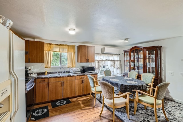 kitchen featuring sink, appliances with stainless steel finishes, a wall mounted AC, light hardwood / wood-style floors, and a textured ceiling