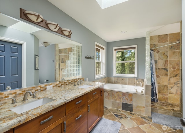 bathroom with tasteful backsplash, vanity, plus walk in shower, and a skylight