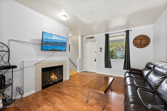 living room with a tile fireplace and hardwood / wood-style floors