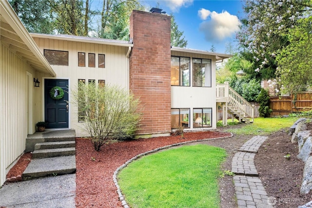 exterior space with fence, stairs, a sunroom, and a chimney