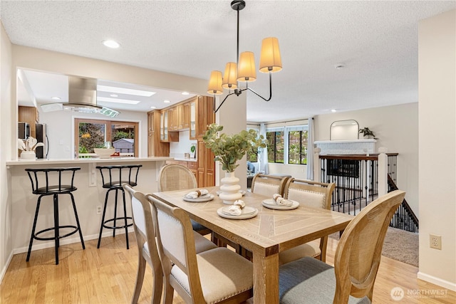 dining room featuring baseboards, recessed lighting, light wood-style floors, and a textured ceiling