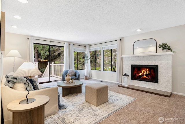 living area with carpet floors, baseboards, a textured ceiling, and a fireplace