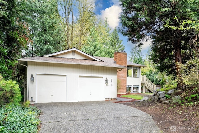 view of home's exterior featuring an attached garage, aphalt driveway, stairs, and a chimney