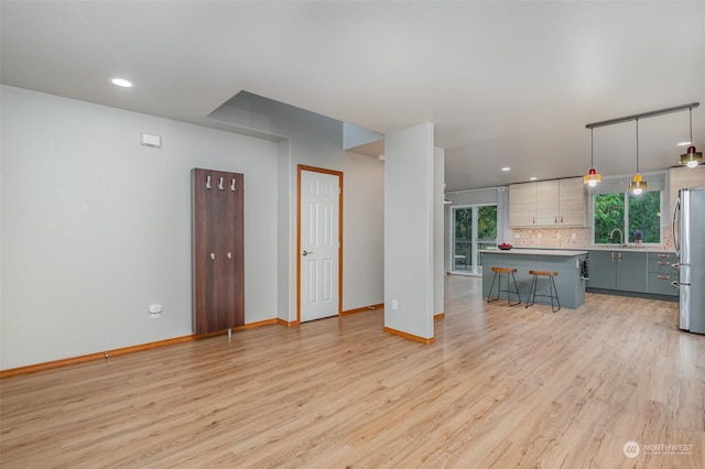 unfurnished living room with sink and light hardwood / wood-style flooring