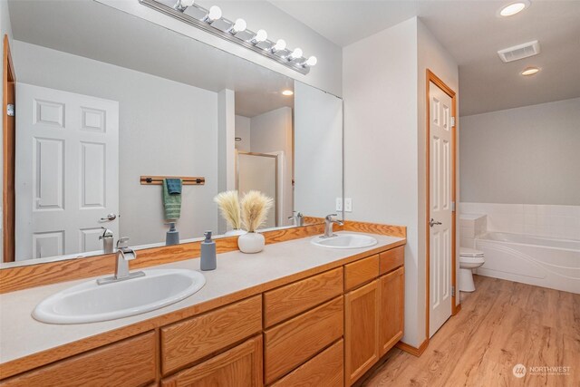 full bathroom featuring vanity, toilet, hardwood / wood-style floors, and shower with separate bathtub