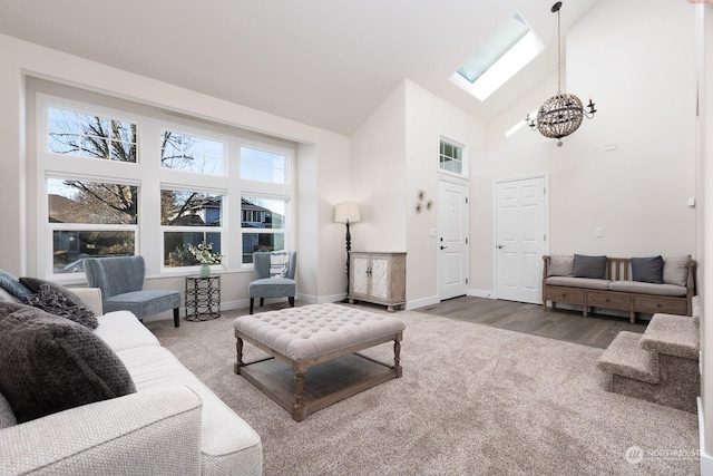 living room with carpet, a notable chandelier, high vaulted ceiling, and a skylight