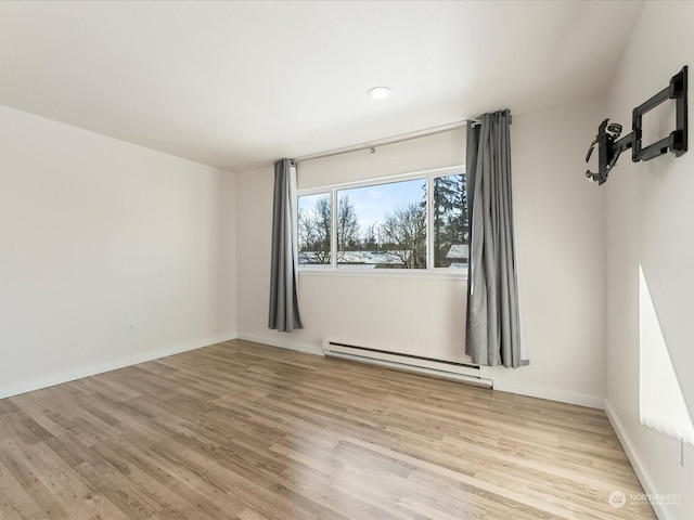 unfurnished room featuring a baseboard heating unit and light wood-type flooring