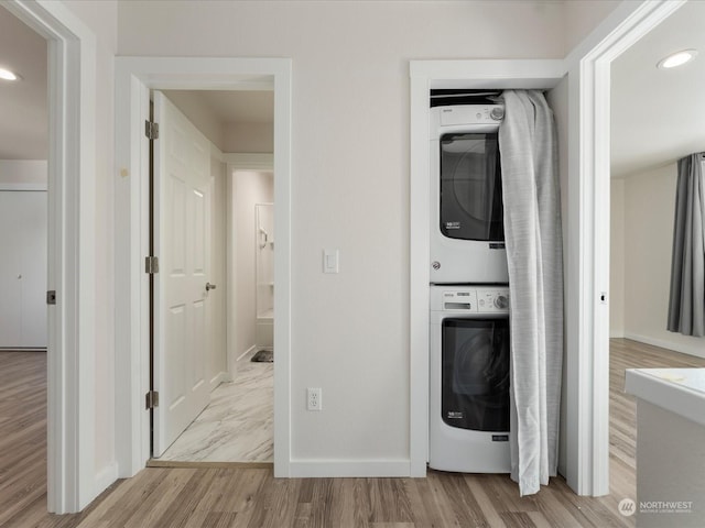 washroom featuring stacked washer / drying machine and light hardwood / wood-style flooring