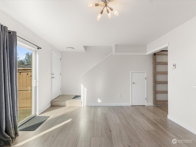 spare room featuring light hardwood / wood-style floors and a notable chandelier