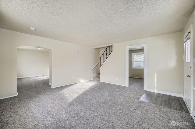 unfurnished room with dark colored carpet and a textured ceiling