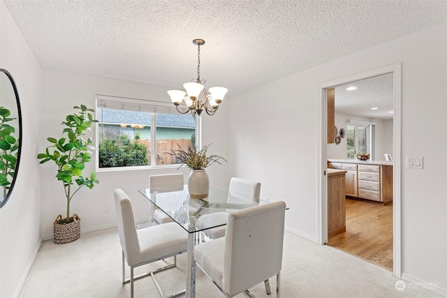 carpeted dining area featuring an inviting chandelier, a wealth of natural light, and a textured ceiling