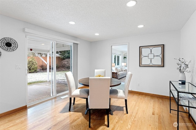 dining room with light hardwood / wood-style flooring and a textured ceiling