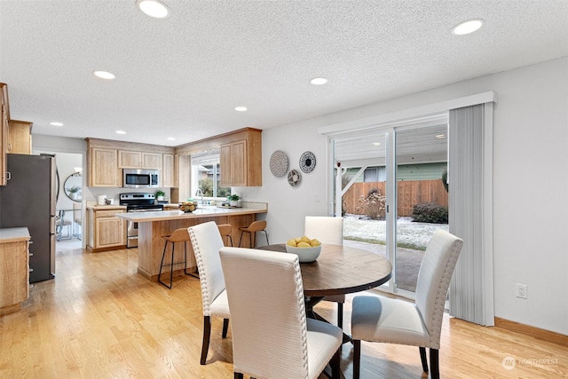 dining room with sink, a textured ceiling, and light wood-type flooring