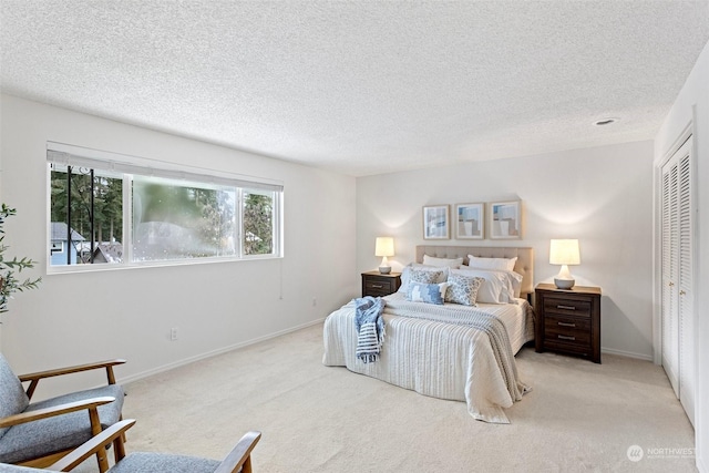 bedroom featuring light carpet, a textured ceiling, and a closet