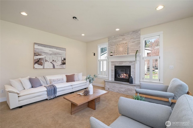 carpeted living area with recessed lighting, plenty of natural light, and a stone fireplace