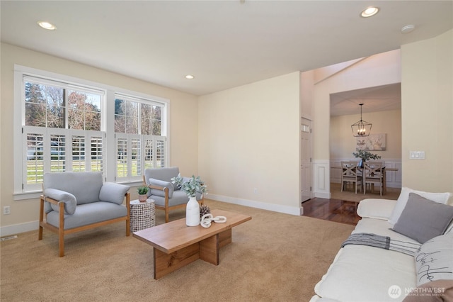 carpeted living room featuring baseboards, recessed lighting, and an inviting chandelier