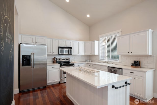 kitchen featuring stainless steel appliances, dark wood-style flooring, a sink, white cabinets, and decorative backsplash