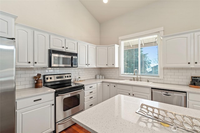 kitchen featuring white cabinetry, appliances with stainless steel finishes, decorative backsplash, and a sink