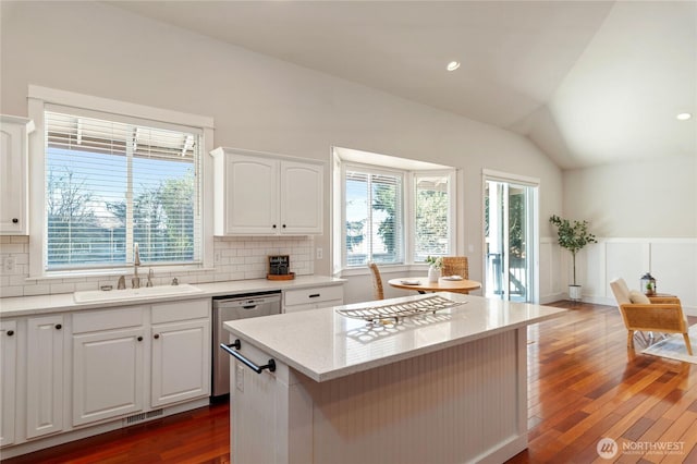 kitchen featuring tasteful backsplash, plenty of natural light, dishwasher, vaulted ceiling, and a sink