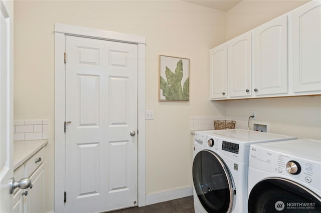 washroom featuring washing machine and clothes dryer, cabinet space, and baseboards