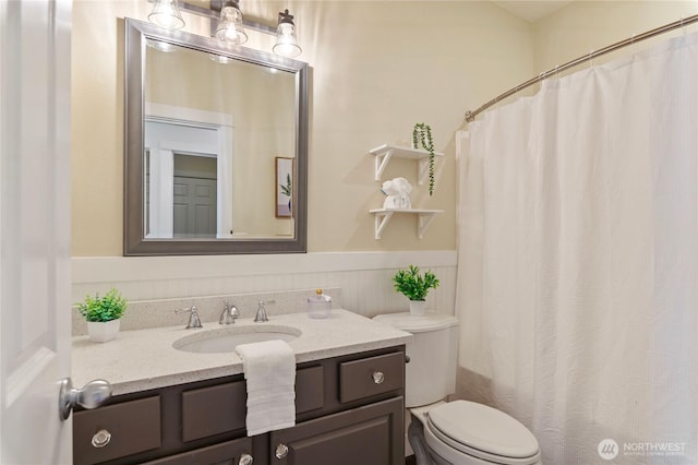 full bath featuring curtained shower, a wainscoted wall, vanity, and toilet