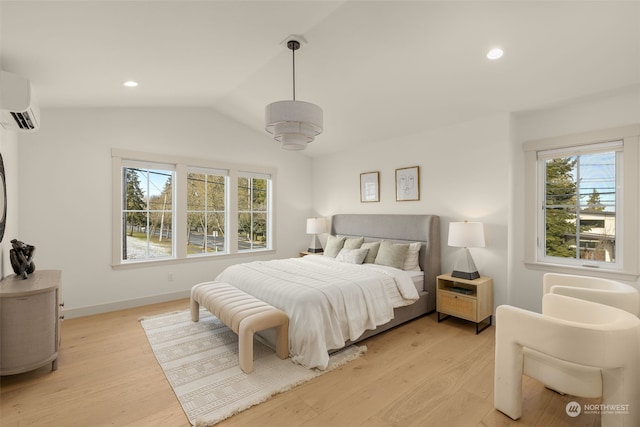 bedroom featuring vaulted ceiling, light wood-type flooring, and a wall unit AC