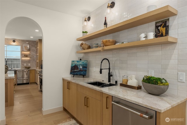 kitchen featuring sink, light hardwood / wood-style flooring, stainless steel dishwasher, light stone countertops, and decorative backsplash