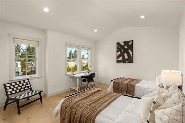 bedroom with multiple windows, lofted ceiling, and light hardwood / wood-style flooring