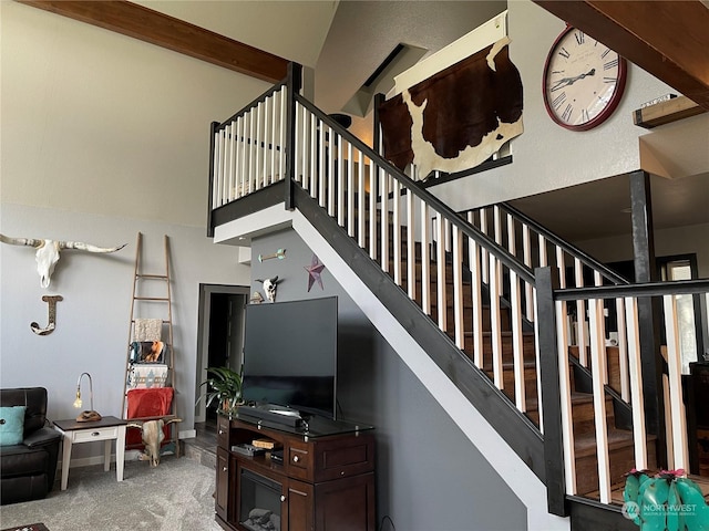 stairway with beamed ceiling, carpet, and a high ceiling