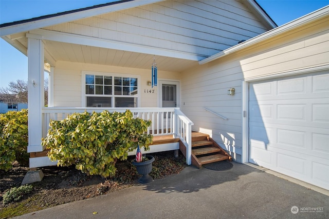 doorway to property featuring a garage and a porch