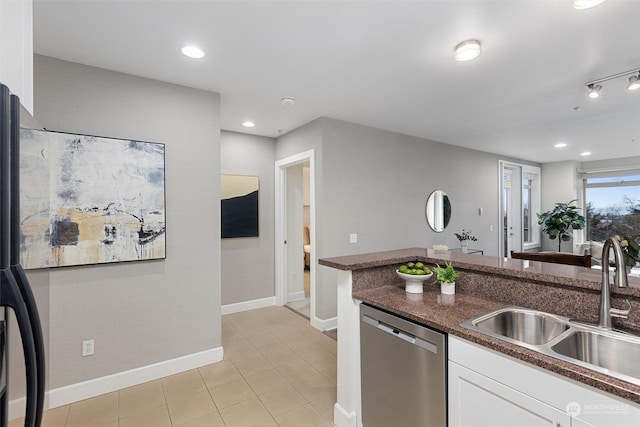 kitchen featuring light tile patterned flooring, sink, white cabinets, dark stone counters, and stainless steel dishwasher