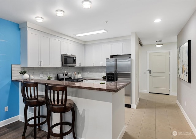 kitchen featuring appliances with stainless steel finishes, a breakfast bar area, white cabinets, and kitchen peninsula