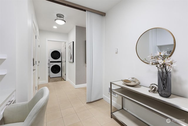 hall with stacked washer and clothes dryer and light tile patterned floors