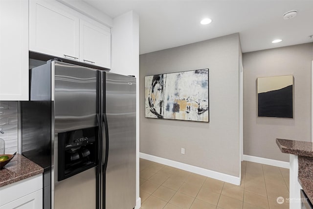 kitchen with stainless steel refrigerator with ice dispenser, dark stone countertops, white cabinets, and light tile patterned floors