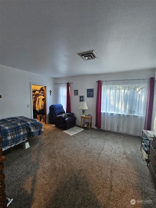 carpeted bedroom with a walk in closet, a textured ceiling, and a closet