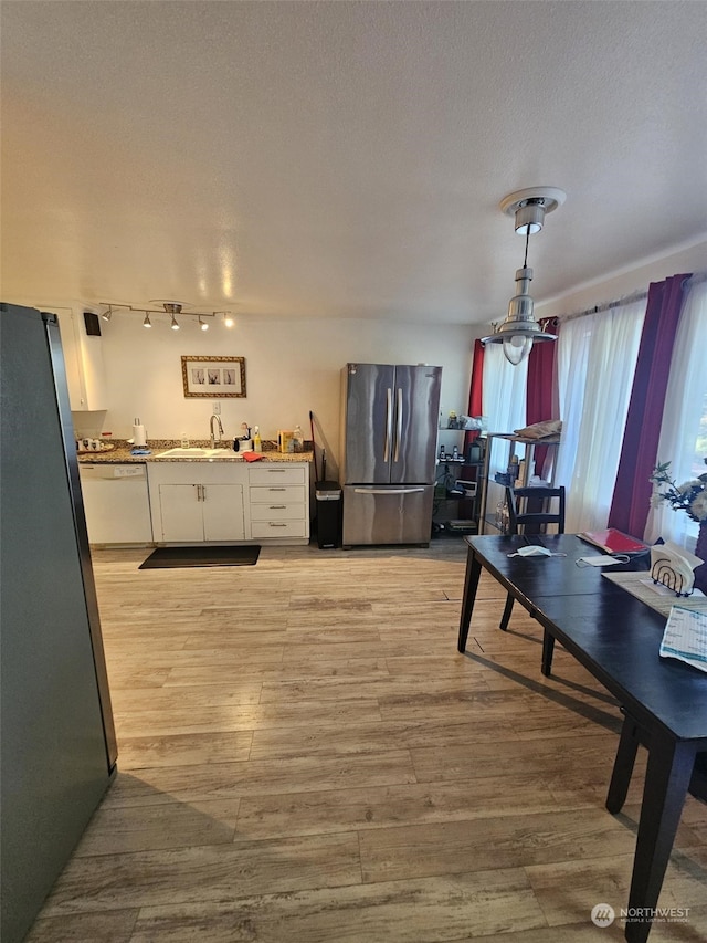 dining area with sink, light hardwood / wood-style floors, and a textured ceiling