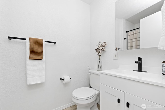 bathroom featuring toilet, baseboards, and vanity