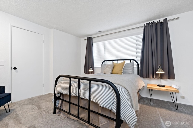 bedroom featuring carpet, visible vents, and a textured ceiling