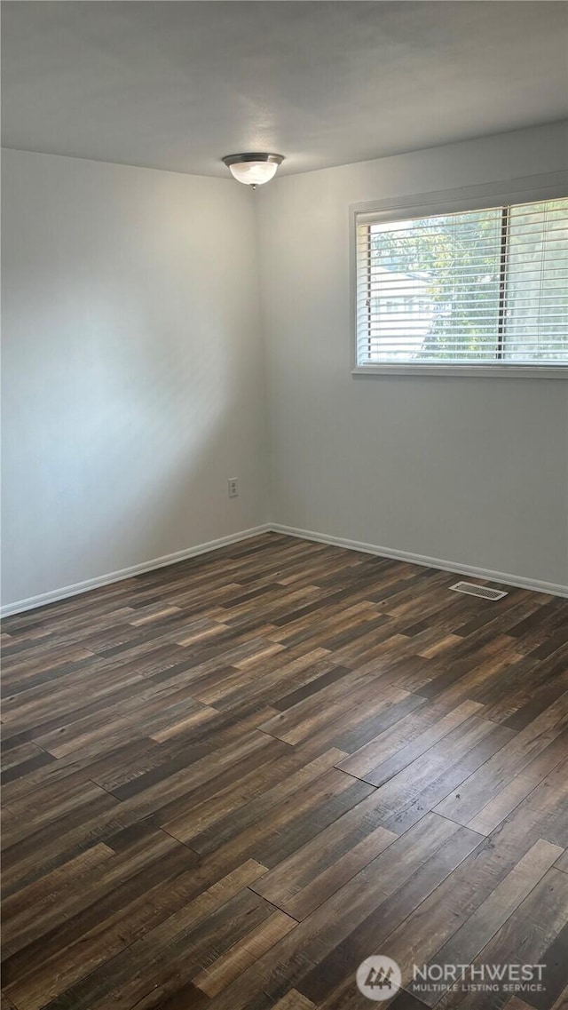 spare room with dark wood-type flooring and baseboards