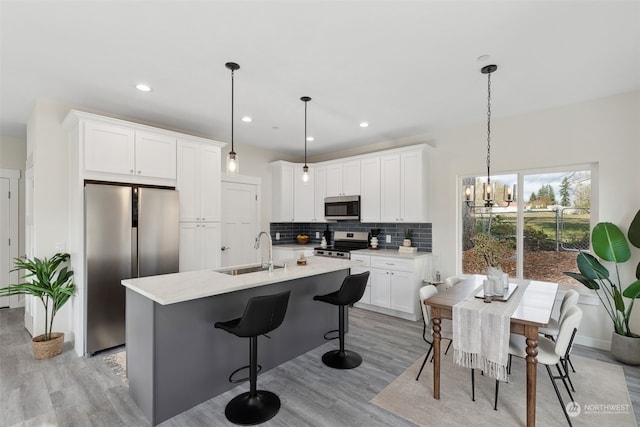 kitchen featuring pendant lighting, stainless steel appliances, sink, and white cabinets