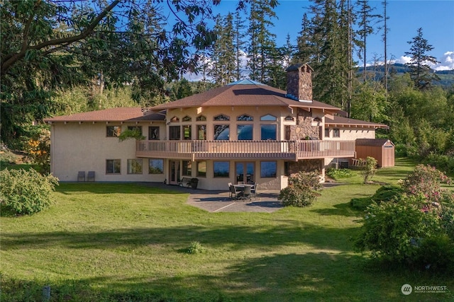 back of property with a wooden deck, a yard, a patio, and a storage unit